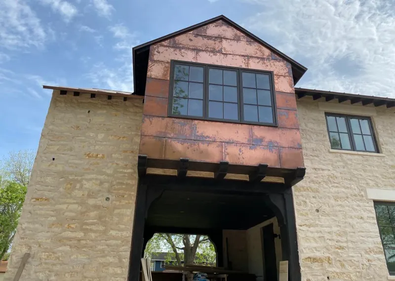 Copper metal panel facade on a stone building for Roof Repair in Holly